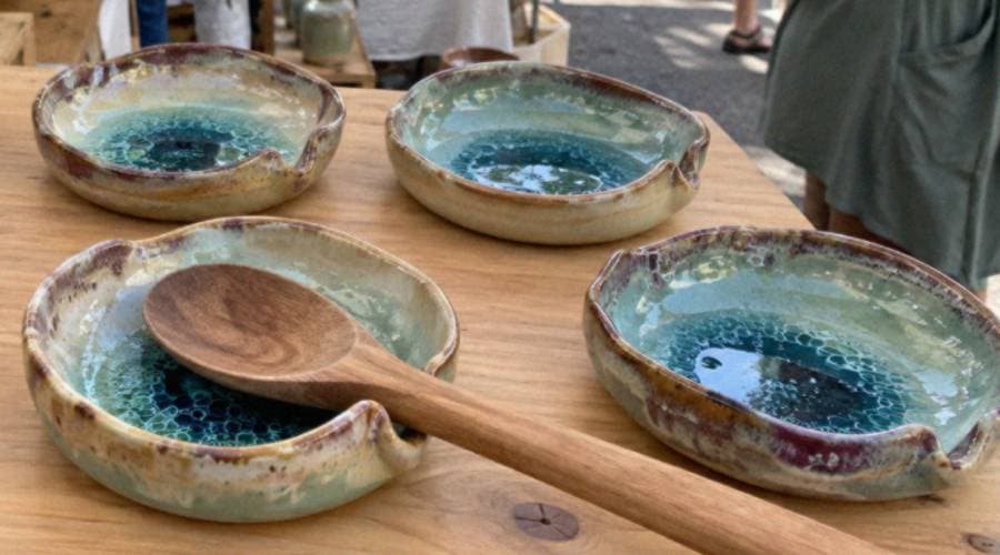 Handmade ceramic bowls with a teal glaze and a wooden serving spoon